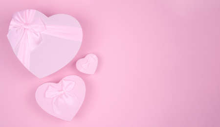 Pink heart-shaped gift with bow for Valentine's Day on a pink background, minimalism.の写真素材