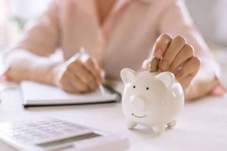 Old women's hands put money in the piggy Bank, the concept of retirement, savings.の写真素材