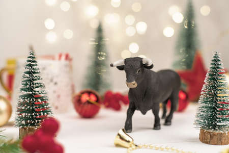 decorative bull, symbol of the New Year on the background of Christmas trees and Golden bokeh.の写真素材