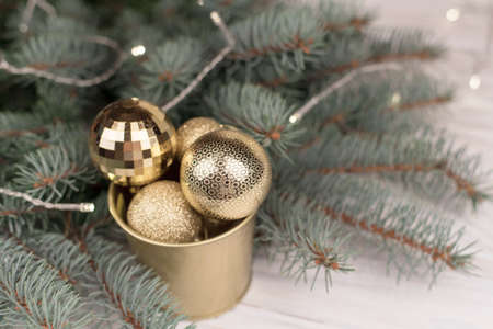 Stylish bucket of Christmas Golden toys on a wooden background and branches of Christmas trees.の写真素材