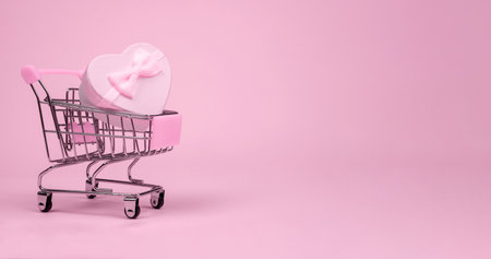 Pink heart gift with bow for Valentines Day in shopping scart on a pink background, banerの写真素材