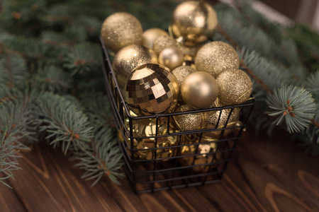 Stylish box of Christmas Golden toys on a wooden background and branches of Christmas trees. Copy spaceの写真素材