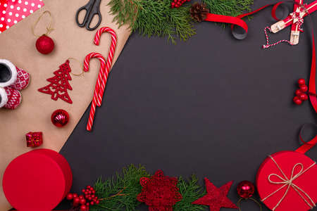 Gift wrapping. Packaging modern christmas present boxes in stylish gray paper with satin red ribbon. Top view table with fir tree branches, decoration of gift.の写真素材