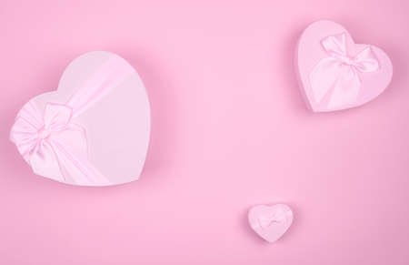 Pink heart-shaped gift with bow for Valentine's Day on a pink background, minimalism.の写真素材