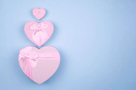 Pink heart-shaped gift with bow for Valentine's Day on a blue background, minimalism.の写真素材