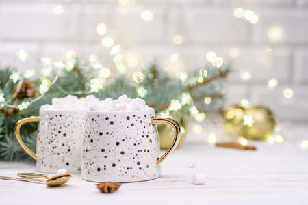 White cup of cappuccino or cocoa with christmas tree on the buckground of gold bokeh, New Year hot drink.の写真素材