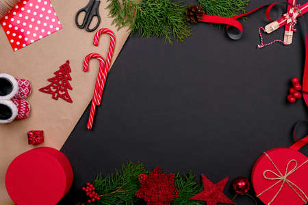 Gift wrapping. Packaging modern christmas present boxes in stylish gray paper with satin red ribbon. Top view table with fir tree branches, decoration of gift.の写真素材