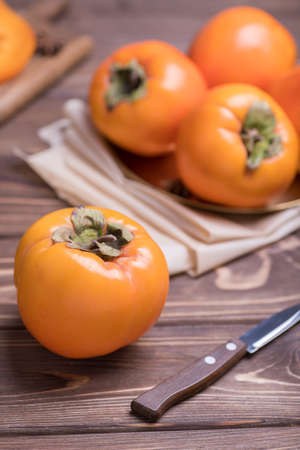 Delicious fresh orange persimmon fruit on wooden table with knifeの写真素材