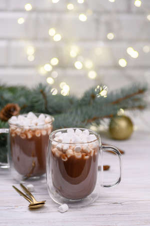 Glass cup of hot cocoa with christmas tree on the buckground of gold bokeh, New Year hot drink.の写真素材