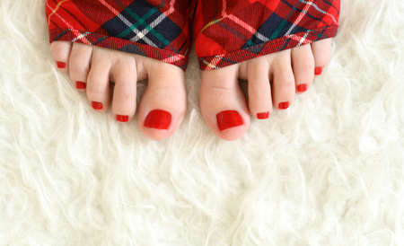 Red winter pedicure on white warm plaid.の写真素材
