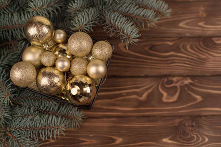 Stylish bucket of Christmas Golden toys on a wooden background and branches of Christmas trees.の写真素材