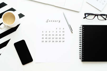 Calendar of February on white desktop flat ley with a cup of coffee and a notebook.の写真素材