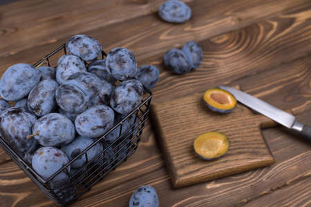 Lots of ripe juicy plums in a bowl on the woodentable.の写真素材