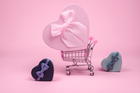Pink big heart-shaped gift with bow for Valentine's Day in shopping scart on a pink background, minimalism.の写真素材