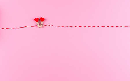 Tender little heart symbol of St. Valentine's day on a clothespin and string creative postcard, copy space, flat lay on pink backgroundの写真素材