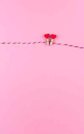 Tender little heart symbol of St. Valentine's day on a clothespin and string creative postcard, copy space, flat lay on pink backgroundの写真素材
