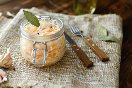 Sour, pickled sauerkraut with carrots and bay leaves in a glass jarの写真素材