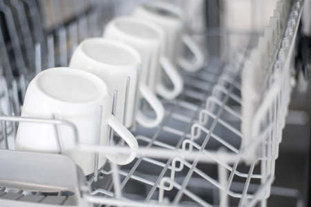 Large white tea mugs are stacked in the dishwasher.の写真素材