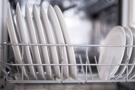 White flat plates large and small are loaded into the dishwasherの写真素材