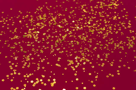 Gold glitter stars on a dark red backgroundの写真素材
