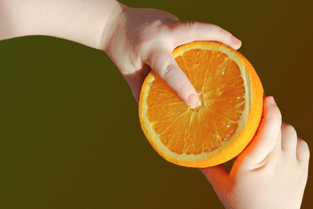 Photo half an orange in his hand a small childの写真素材