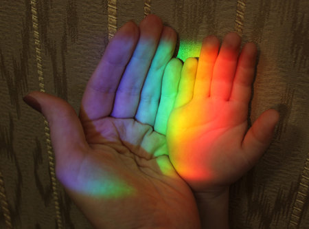 picture of the hand of a child and mother with a rainbow on the background of wallpaper