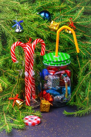 Christmas and New Year decorations and candy canes in cocktail glass jars on a Christmas tree background. The concept of celebrating and decorating Christmas and New Yearの写真素材