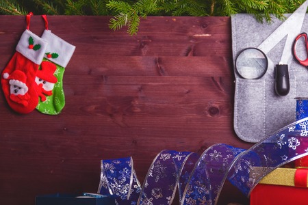 Package christmas gift box. New year christmas wrapping paper, ribbon, bow and thread, scissors, christmas tree on wooden background. Winter time new year. Copy spaceの写真素材