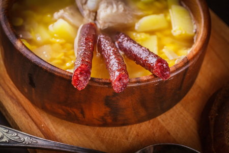 Pea soup with potatoes, pork ribs and pickled sausages in a wooden plateの写真素材