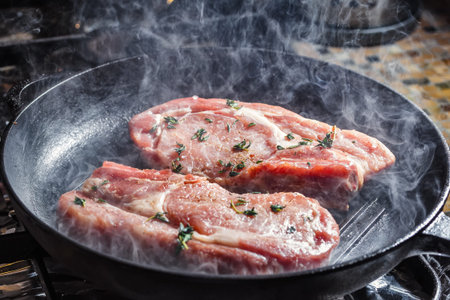 Smoke rises above natural pork cutlets with seasoned pepper, salt, garlic and thyme, frying in a grill panの写真素材