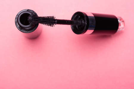 Eyelash makeup brush and mascara bottle close up on pink background with copyspaceの写真素材
