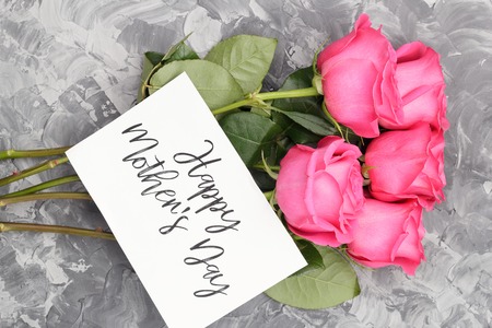 Pink roses and white card with an inscription, Happy Mother's Day, on a gray concrete backgroundの写真素材
