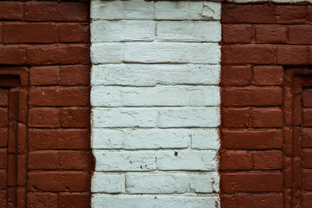 Texture of an old red brick wall background with a strip of white paintの写真素材