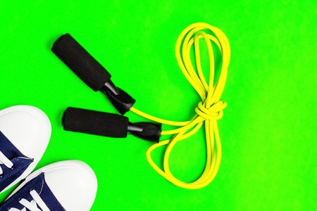 A pair of new stylish sneakers and a skipping rope on a bright green, blue background. View from above. Concept of outdoor activities and healthy lifeの写真素材