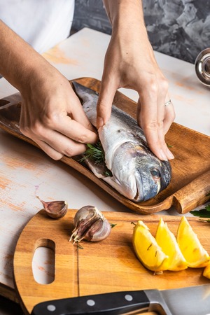 Process of cooking Dorado fish with lemon, olive oil and herbs. Female hands close-up. Concept of homemade food, culinary hobbyの写真素材