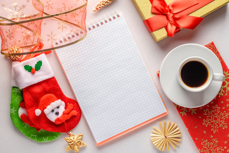 A cup of coffee on a saucer in female hands against the background of bright Christmas napkin on a white table. Flat lay. Top view, Copy spaceの写真素材