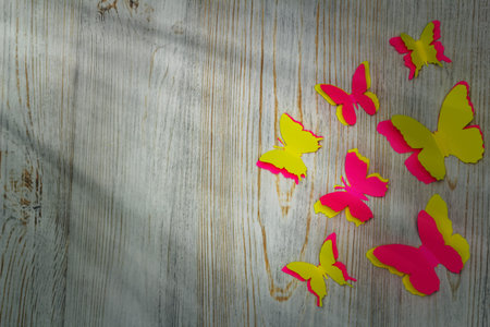 Colorful paper butterflies on wooden background. Childrens developmental activity. Application and origami. Copy spaceの写真素材