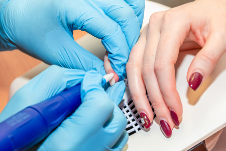 Manicure process close-up. Removing old decorative nail polish with milling machineの写真素材