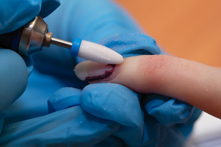 Manicure process close-up. Removing old decorative nail polish with milling machineの写真素材