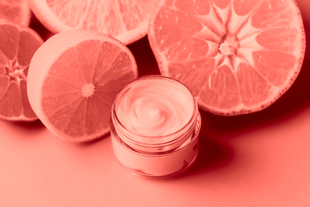 Face cream and citrus on a bright blue background. Cosmetics from natural ingredients natural concept. Toning living coral.の写真素材