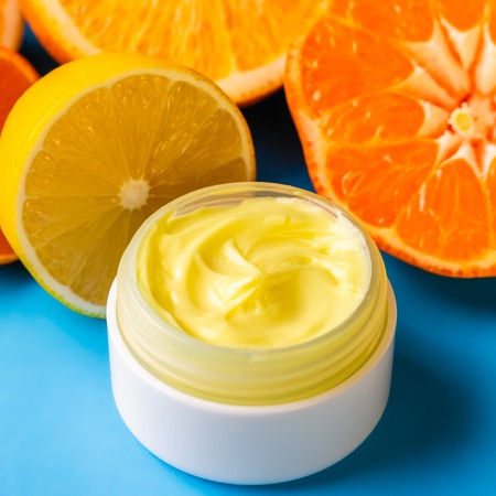Face cream and citrus on a bright blue background. Cosmetics from natural ingredients natural concept.の写真素材