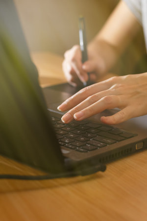 Illustrator using a graphics tablet. Woman's retoucher's hands using laptop and drawing tablet.