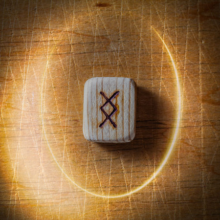 Ingwaz. Handmade scandinavian wooden runes on a wooden vintage background in a circle of light....