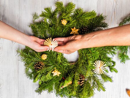 Two women decorate a Christmas wreath of spruce branches together. Relationship and friendship concept.の写真素材