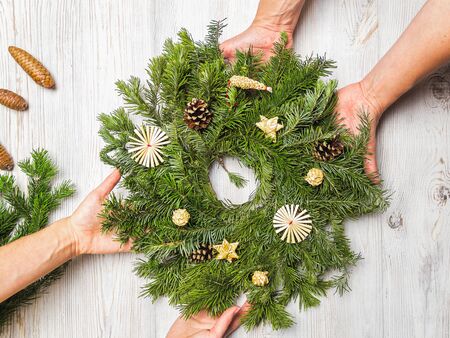 Two women decorate a Christmas wreath of spruce branches together. Relationship and friendship concept.の写真素材