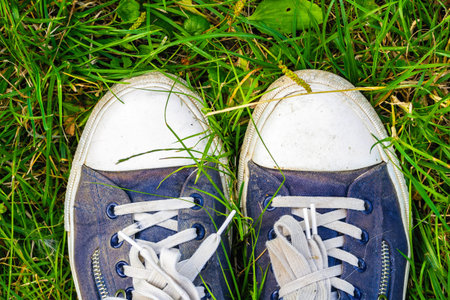 Old, dirty, shabby sneakers on the green grass. Hiking Travel Concept.