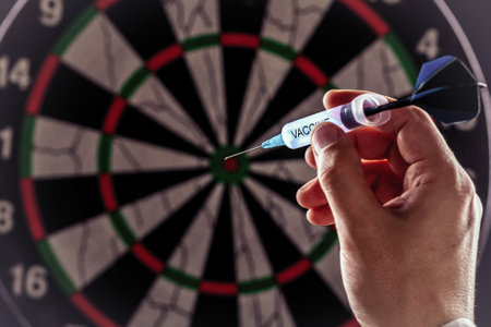 Throwing syringe in the form of a dart with the inscription vaccine hand into a dartboard. Coronavirus vaccine concept.の写真素材