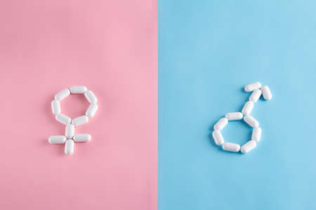 Female and male gender symbols are lined up from pills on pink and blue backgrounds. Venus and Marsの写真素材