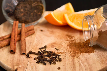 Cinnamon sticks, allspice and pieces of orange on wood boardの写真素材
