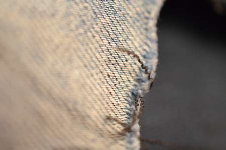 blue texture maden from a piece of jeans with torned hole with threads blurred tonedの写真素材